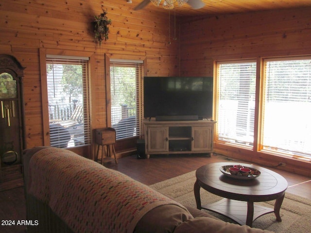 living room featuring wooden walls, a ceiling fan, and wood finished floors