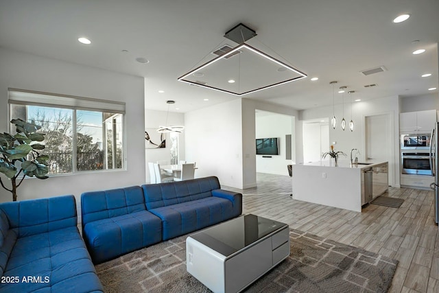 living room featuring sink and light hardwood / wood-style flooring