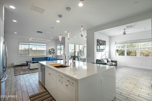 kitchen featuring ceiling fan, sink, white cabinetry, a kitchen island with sink, and stainless steel appliances