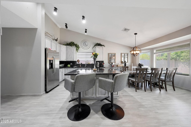 11446 N 109th St, Scottsdale, AZ 85259 - kitchen featuring stainless steel fridge with ice dispenser, dark countertops, white cabinetry, light wood-type flooring, and a kitchen breakfast bar