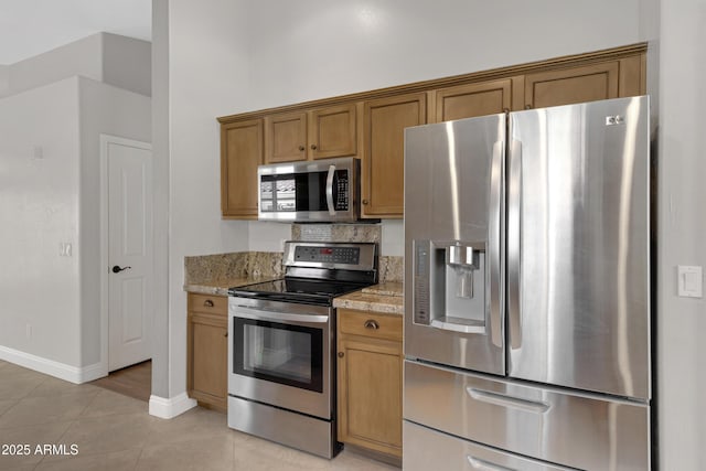 kitchen with light stone countertops, appliances with stainless steel finishes, and light tile patterned floors