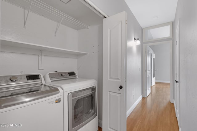 clothes washing area featuring washer and clothes dryer and light wood-type flooring