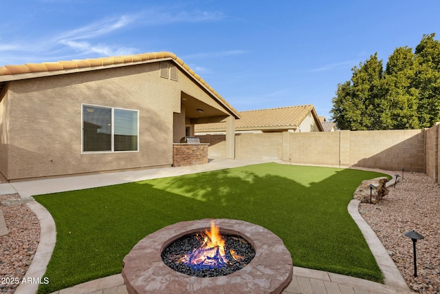 view of yard with exterior kitchen, a patio area, and a fire pit