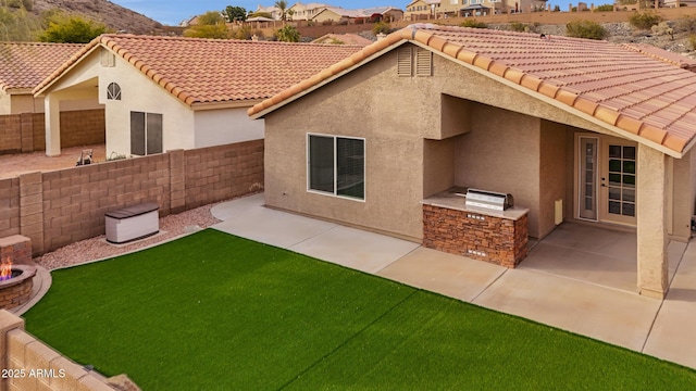 back of property with a yard, a patio area, and an outdoor kitchen