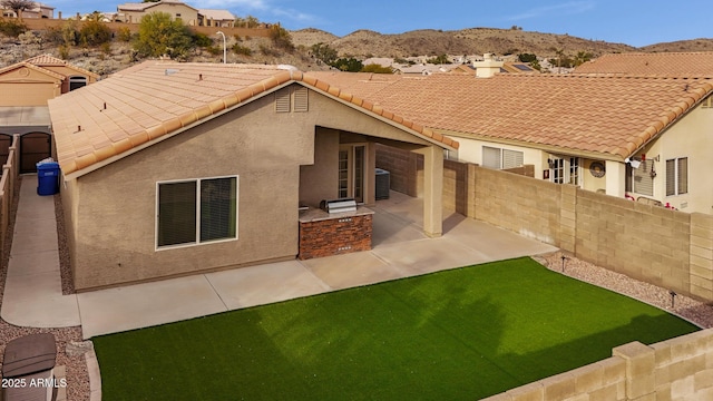 rear view of house featuring area for grilling, a mountain view, and a patio