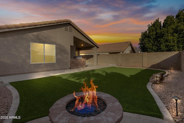 yard at dusk featuring a patio, exterior kitchen, and a fire pit