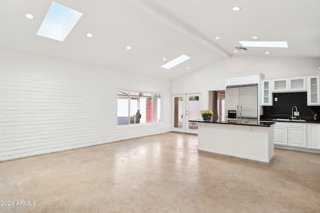 kitchen with beam ceiling, decorative backsplash, sink, white cabinetry, and stainless steel built in refrigerator