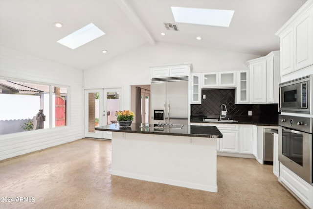 kitchen featuring a skylight, white cabinetry, built in appliances, a kitchen island, and beamed ceiling