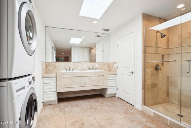 bathroom featuring a skylight, decorative backsplash, stacked washer / dryer, walk in shower, and vanity