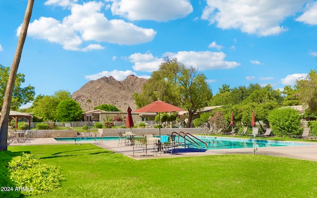 view of pool with a mountain view and a yard