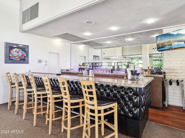 kitchen with light stone countertops, a kitchen breakfast bar, and dark colored carpet