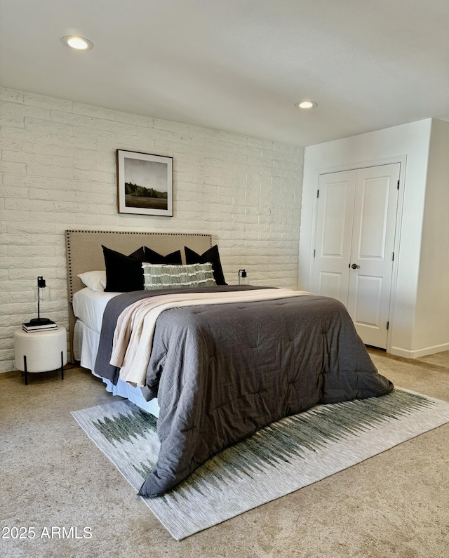 bedroom with light colored carpet, brick wall, and a closet