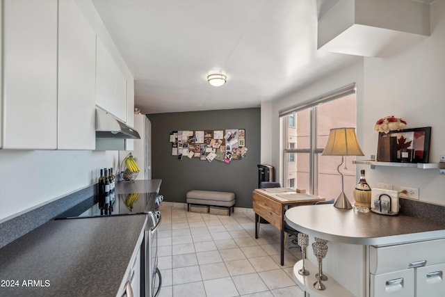 kitchen with light tile patterned floors, white cabinetry, and stainless steel range with electric stovetop