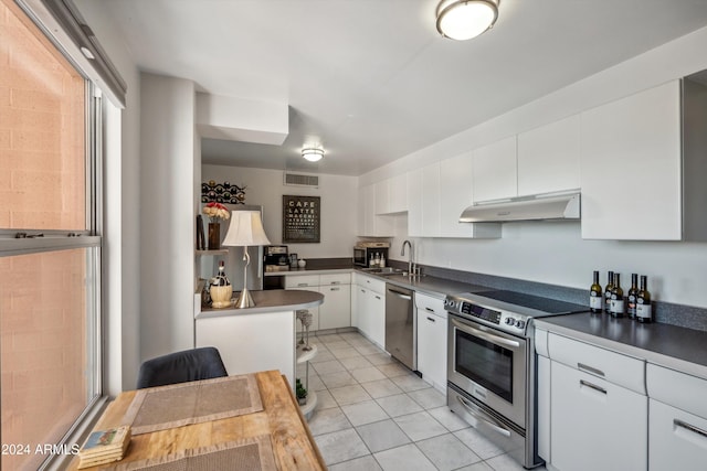 kitchen featuring appliances with stainless steel finishes, light tile patterned floors, white cabinetry, and sink