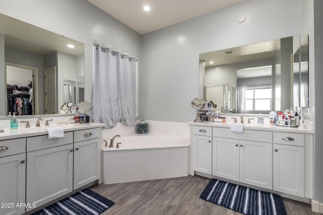 18474 W College Dr, Goodyear, AZ 85395 - bathroom featuring wood finished floors, two vanities, a bath, a spacious closet, and recessed lighting
