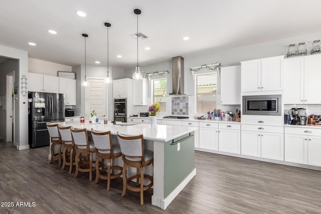 18474 W College Dr, Goodyear, AZ 85395 - kitchen with wall chimney exhaust hood, appliances with stainless steel finishes, backsplash, a center island with sink, and light countertops