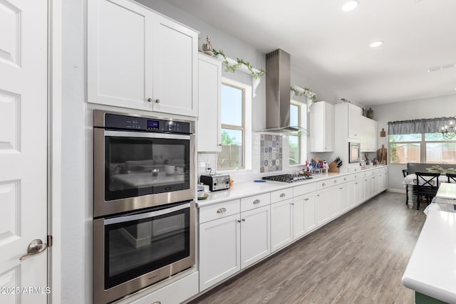 18474 W College Dr, Goodyear, AZ 85395 - kitchen with wall chimney range hood, stainless steel appliances, light wood-style floors, healthy amount of natural light, and recessed lighting