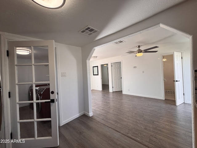 empty room with ceiling fan, dark wood-type flooring, and a textured ceiling