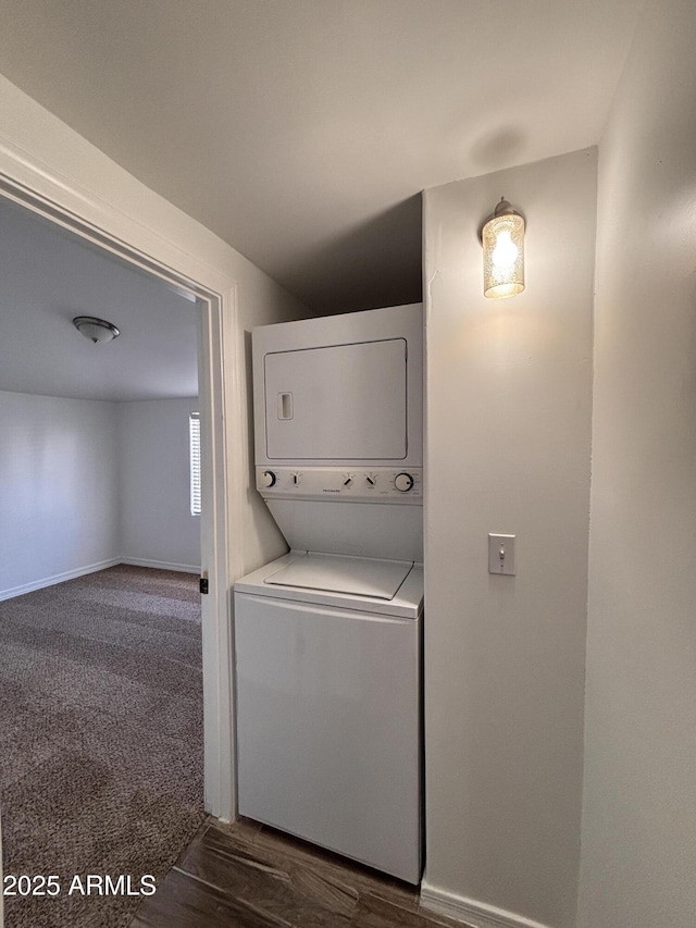 laundry room with stacked washer / drying machine and dark colored carpet