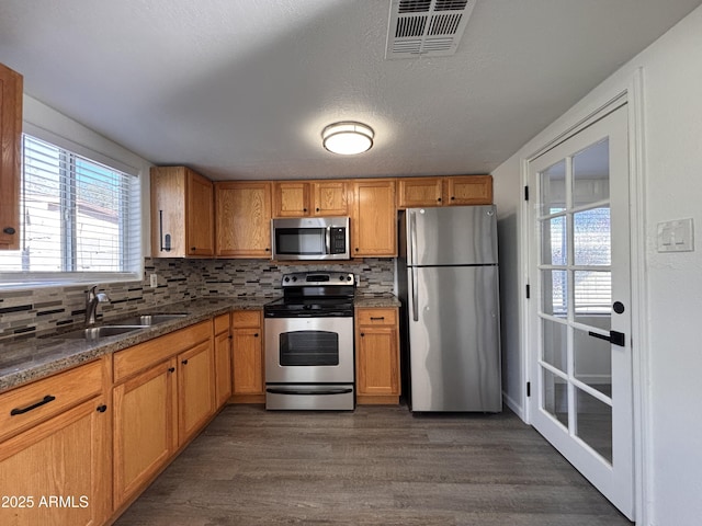 kitchen featuring dark hardwood / wood-style flooring, sink, tasteful backsplash, and appliances with stainless steel finishes