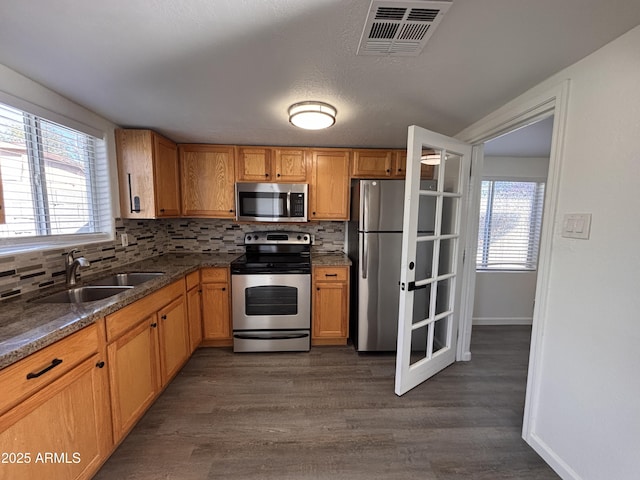 kitchen featuring sink, appliances with stainless steel finishes, dark hardwood / wood-style floors, a wealth of natural light, and decorative backsplash