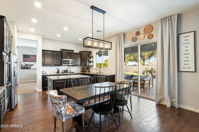 dining area with dark wood-type flooring, sink, and an inviting chandelier