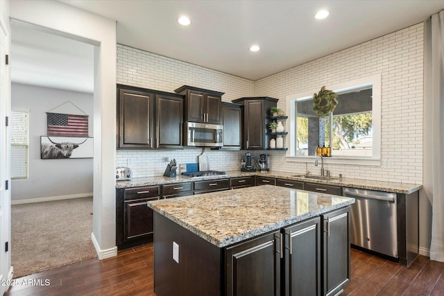 kitchen with a kitchen island, appliances with stainless steel finishes, sink, backsplash, and dark brown cabinetry