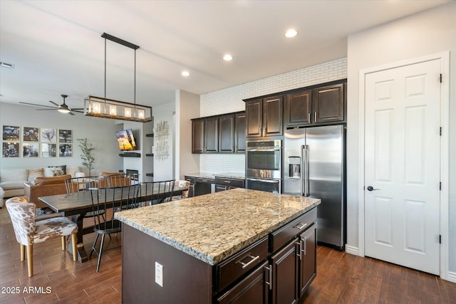 kitchen with pendant lighting, stainless steel appliances, dark hardwood / wood-style floors, a center island, and dark brown cabinetry