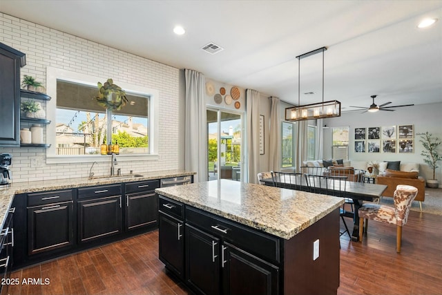 kitchen featuring sink, decorative light fixtures, dark hardwood / wood-style flooring, a kitchen island, and backsplash