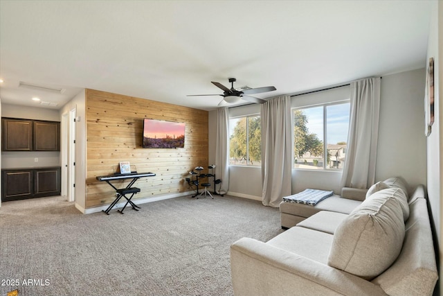 living room with ceiling fan, light colored carpet, and wooden walls