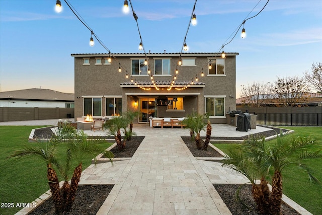 back house at dusk with an outdoor living space with a fire pit and a patio area