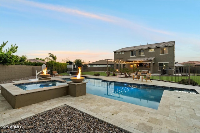 pool at dusk featuring an in ground hot tub, a patio, and a fire pit