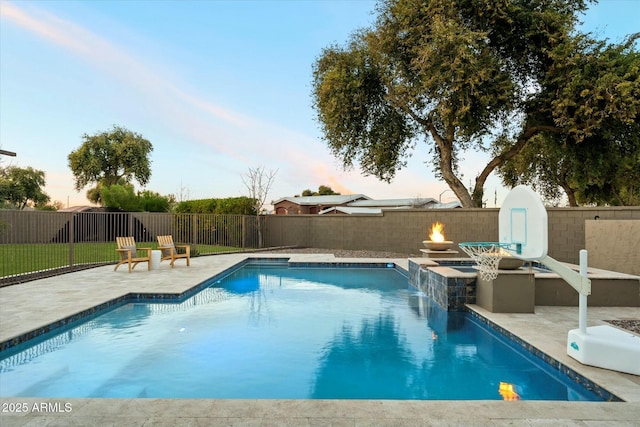 pool at dusk featuring a patio area and an outdoor fire pit