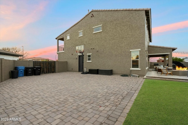 back house at dusk featuring a fire pit and a patio area