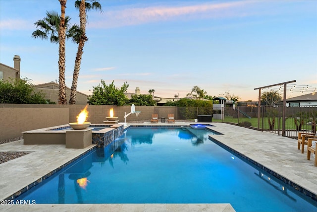 pool at dusk featuring a patio area and an outdoor fire pit