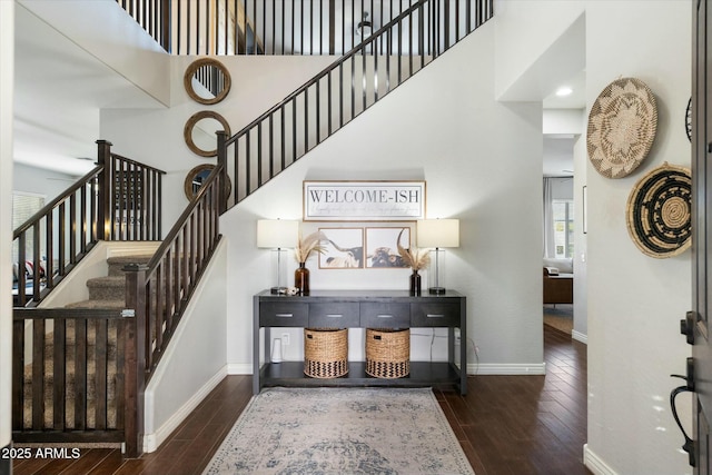 stairway with hardwood / wood-style floors and a towering ceiling