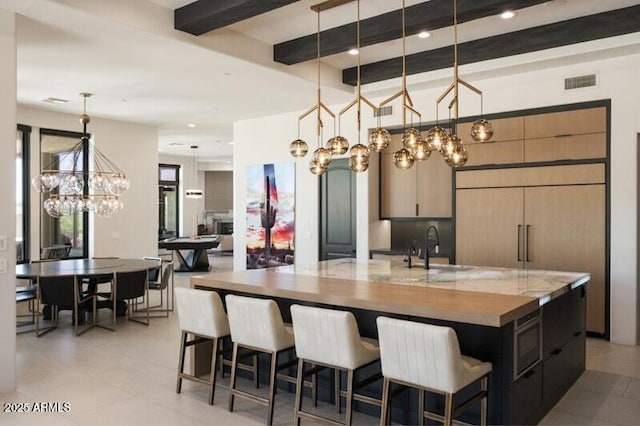 26285 N 89th St, Scottsdale, AZ 85255 - kitchen featuring a chandelier, beamed ceiling, light tile patterned floors, a large island with sink, and hanging light fixtures