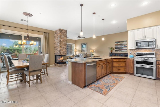 kitchen with light tile patterned flooring, sink, decorative light fixtures, appliances with stainless steel finishes, and backsplash