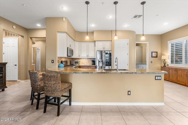 kitchen with pendant lighting, sink, appliances with stainless steel finishes, white cabinetry, and backsplash