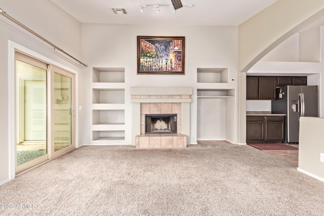 10001 W Potter Dr, Peoria, AZ 85382 - unfurnished living room with built in shelves, carpet flooring, a fireplace, baseboards, and arched walkways