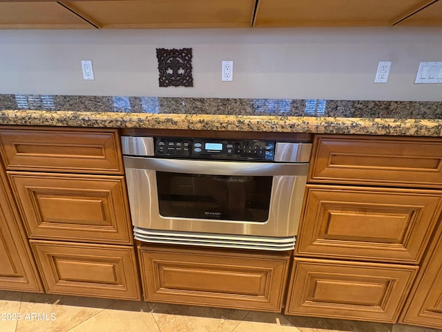 kitchen view of oven, dark countertops, and brown cabinetry