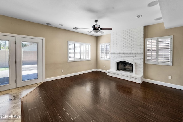 unfurnished living room with ceiling fan, baseboards, a brick fireplace, and wood finished floors