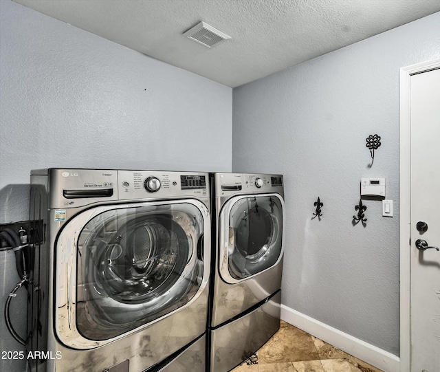 laundry area with independent washer and dryer, baseboards, and a textured ceiling