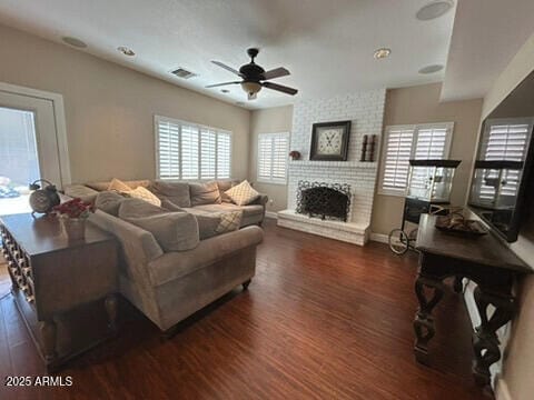 living room featuring wood finished floors, a ceiling fan, a brick fireplace, and baseboards