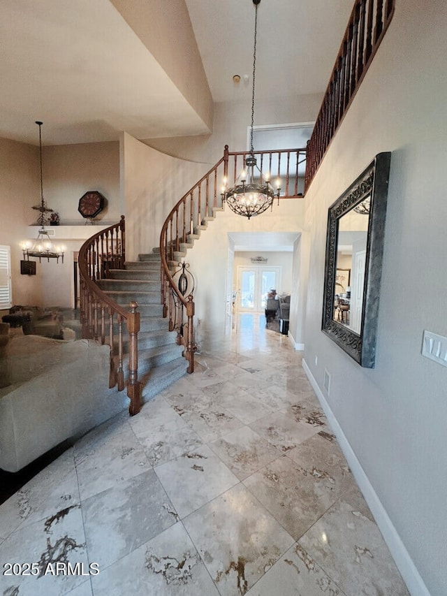 entryway with a chandelier, stairs, baseboards, and a high ceiling