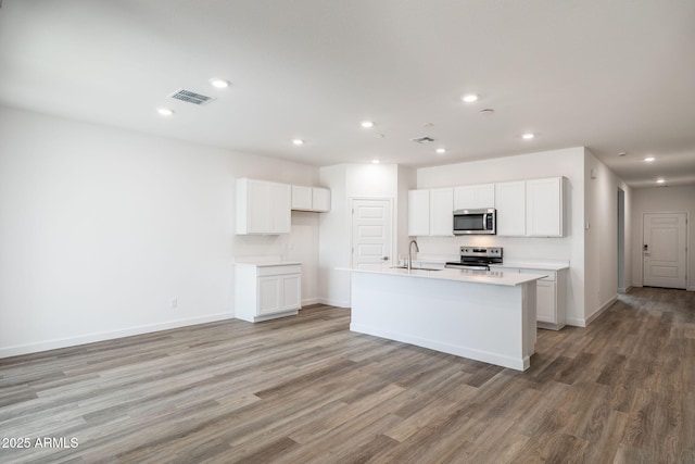 kitchen featuring sink, white cabinetry, a center island with sink, stainless steel appliances, and light hardwood / wood-style floors