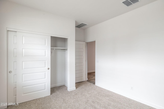 unfurnished bedroom with light colored carpet and a closet