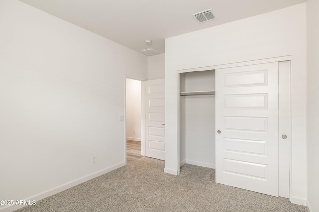 unfurnished bedroom with light colored carpet and a closet