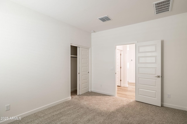 unfurnished bedroom featuring light carpet and a closet