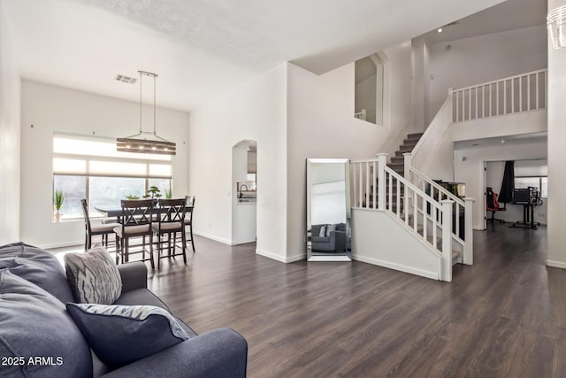 living room featuring dark hardwood / wood-style floors, sink, and a towering ceiling